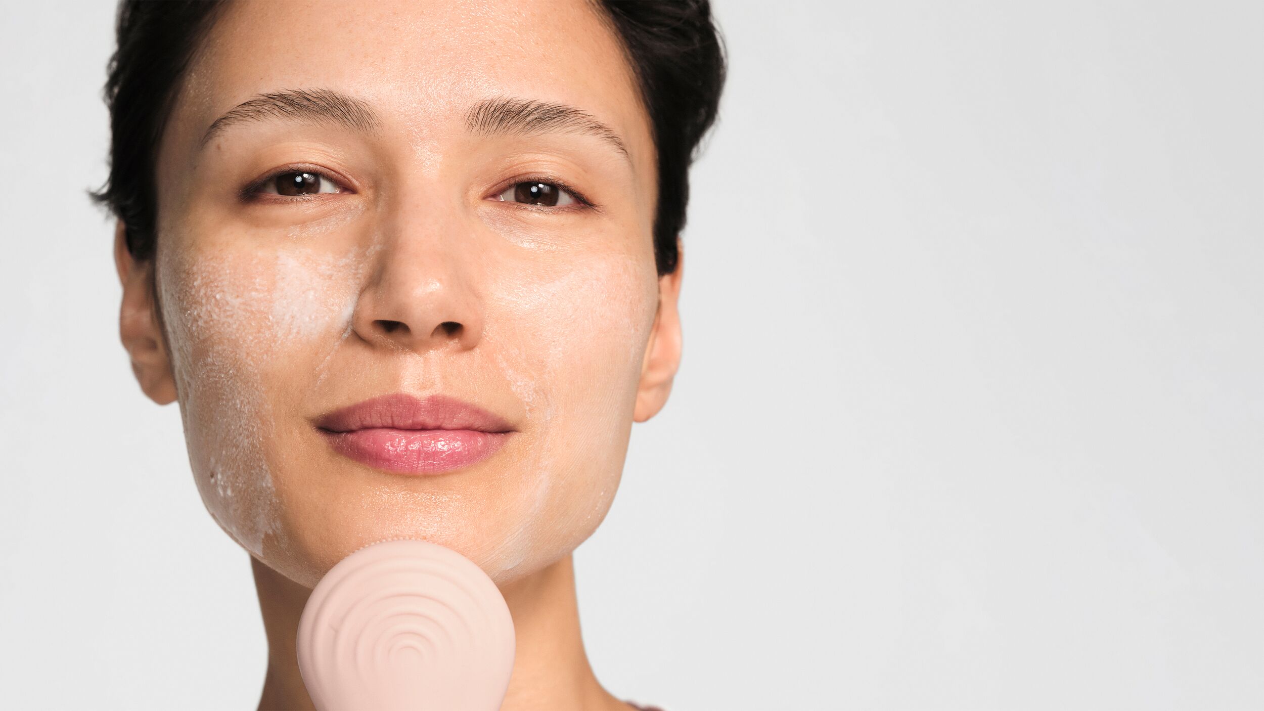 Model cleansing her skin using the cleansing brush